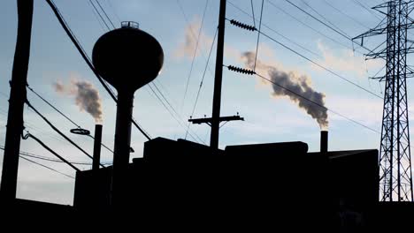 factory silhouette with large tower and two pipes smoke pollution