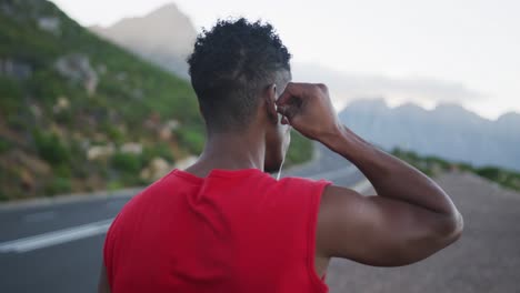 Rear-view-of-african-american-man-wearing-earphones-while-standing-on-the-road