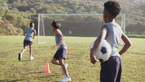 playing soccer, kids practicing drills with cones on school field