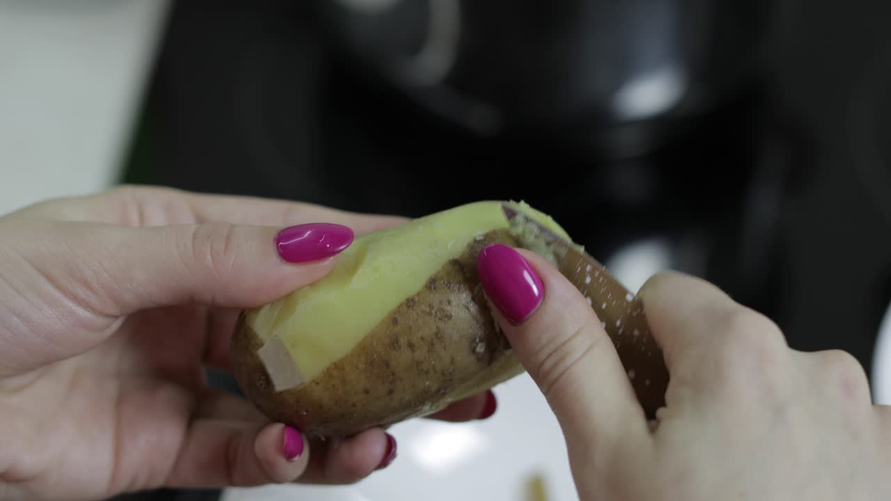 las manos de la ama de casa pelando patatas en la cocina.