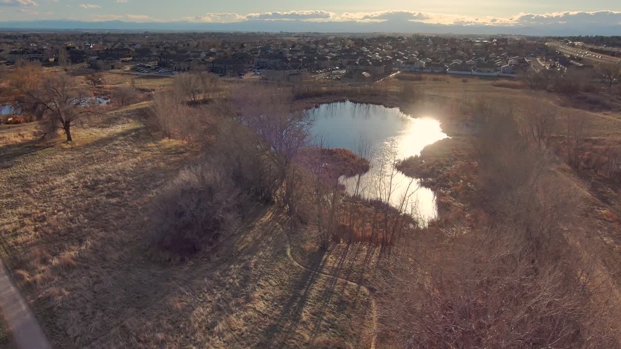 A short drone pan over Greeley Colorado along the front range showing one of the many parks and the Rocky Mountains in the distance