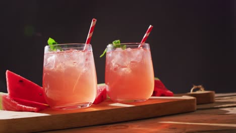 Close-up-of-drinks-with-watermelons-on-wooden-table