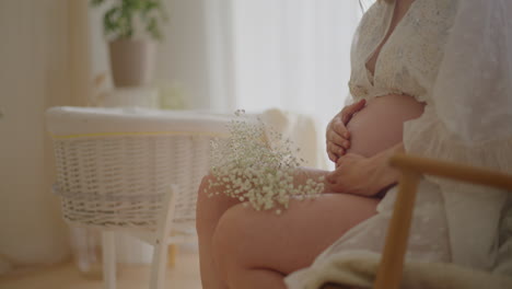 pregnant woman touching belly on chair
