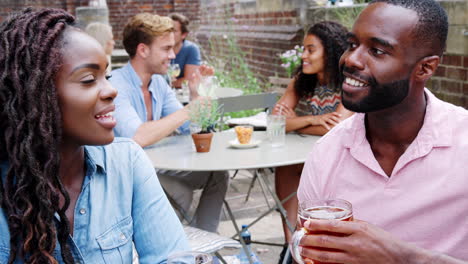 Young-Couple-Meeting-For-Drinks-At-Outdoor-Tables-In-Restaurant