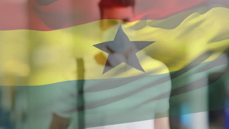 animation of flag of ghana waving over latin man wearing face mask in city street