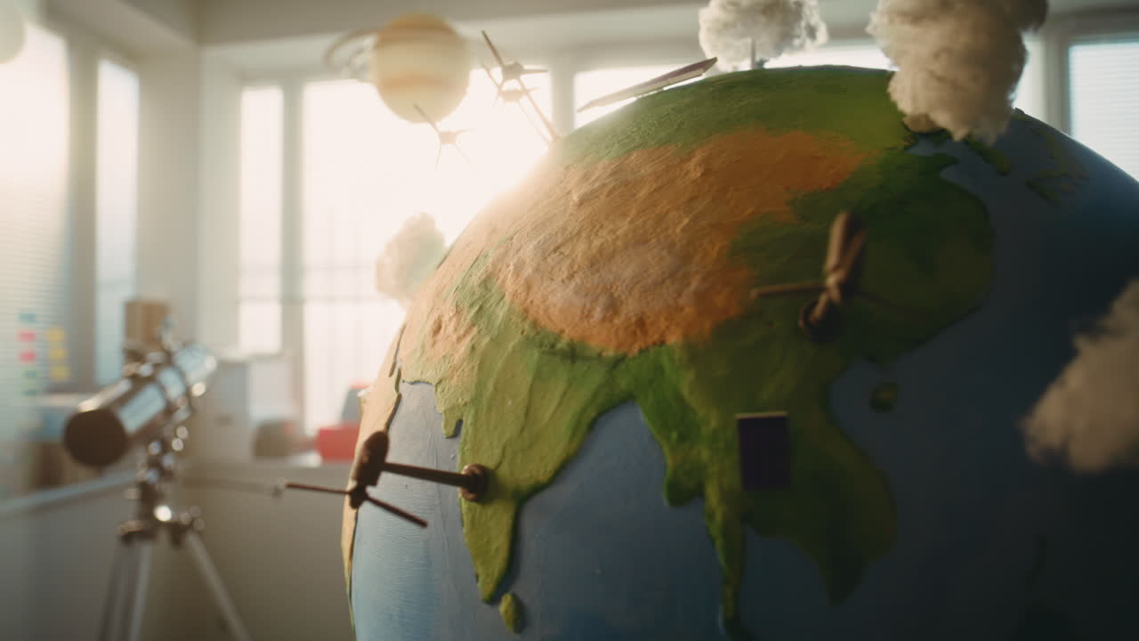 Globe with Miniature 3D Models of Wind Turbines and Solar Panels Hanging in Modern Classroom