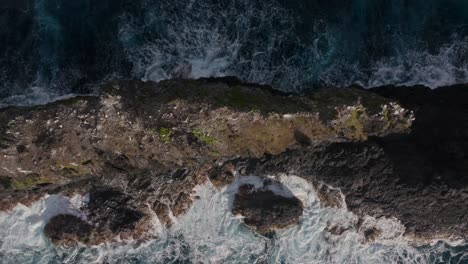 Top-aerial-view-of-eroded-basalt-rock-spiers-with-waves-crashing-off-north-coast-of-Maui,-Hawaii