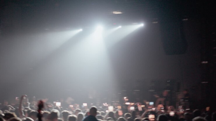 Luci di scena luminose illuminano una folla esultante a un concerto dal vivo