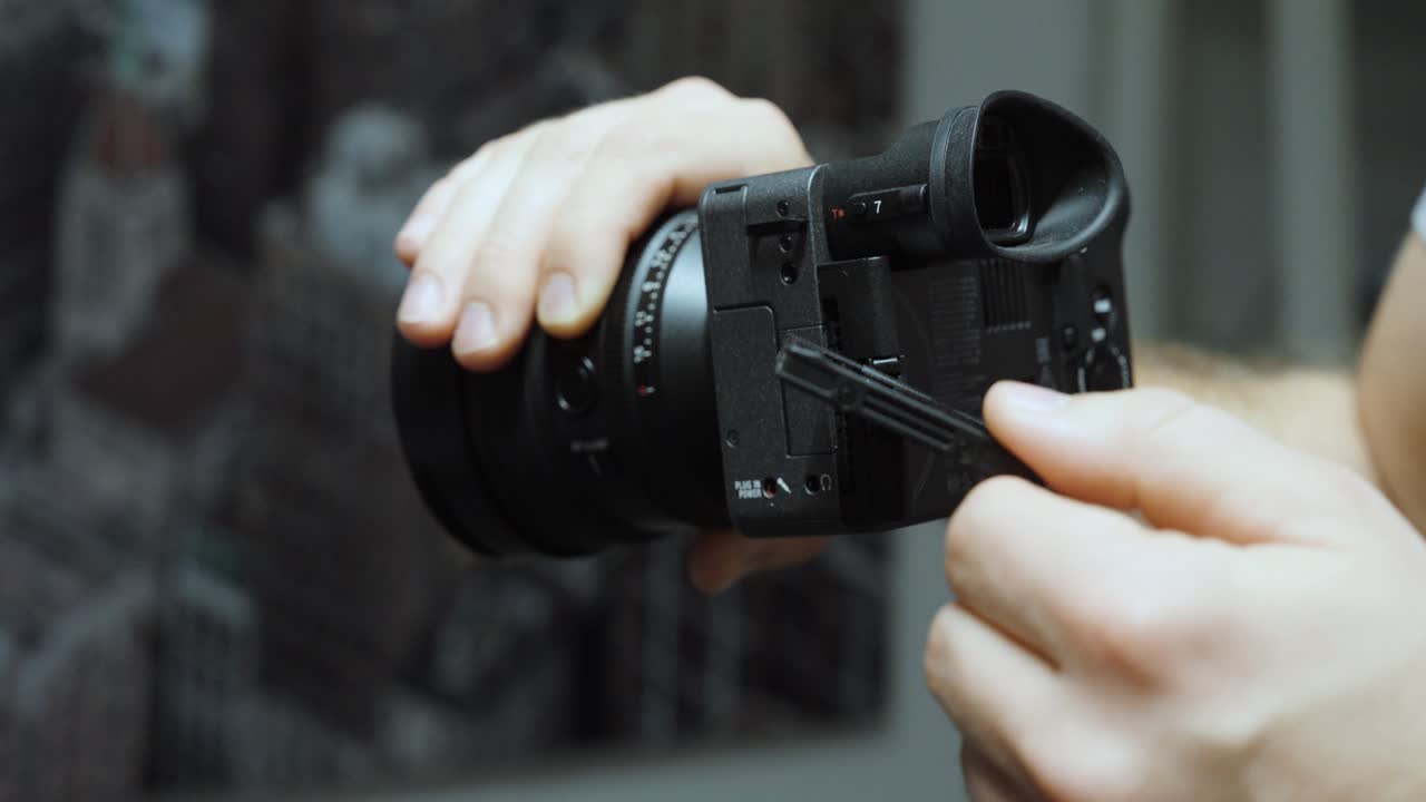 Close-up of a person adjusting a professional camera lens and memory slot. Concept of filmmaking, photography, and creative equipment