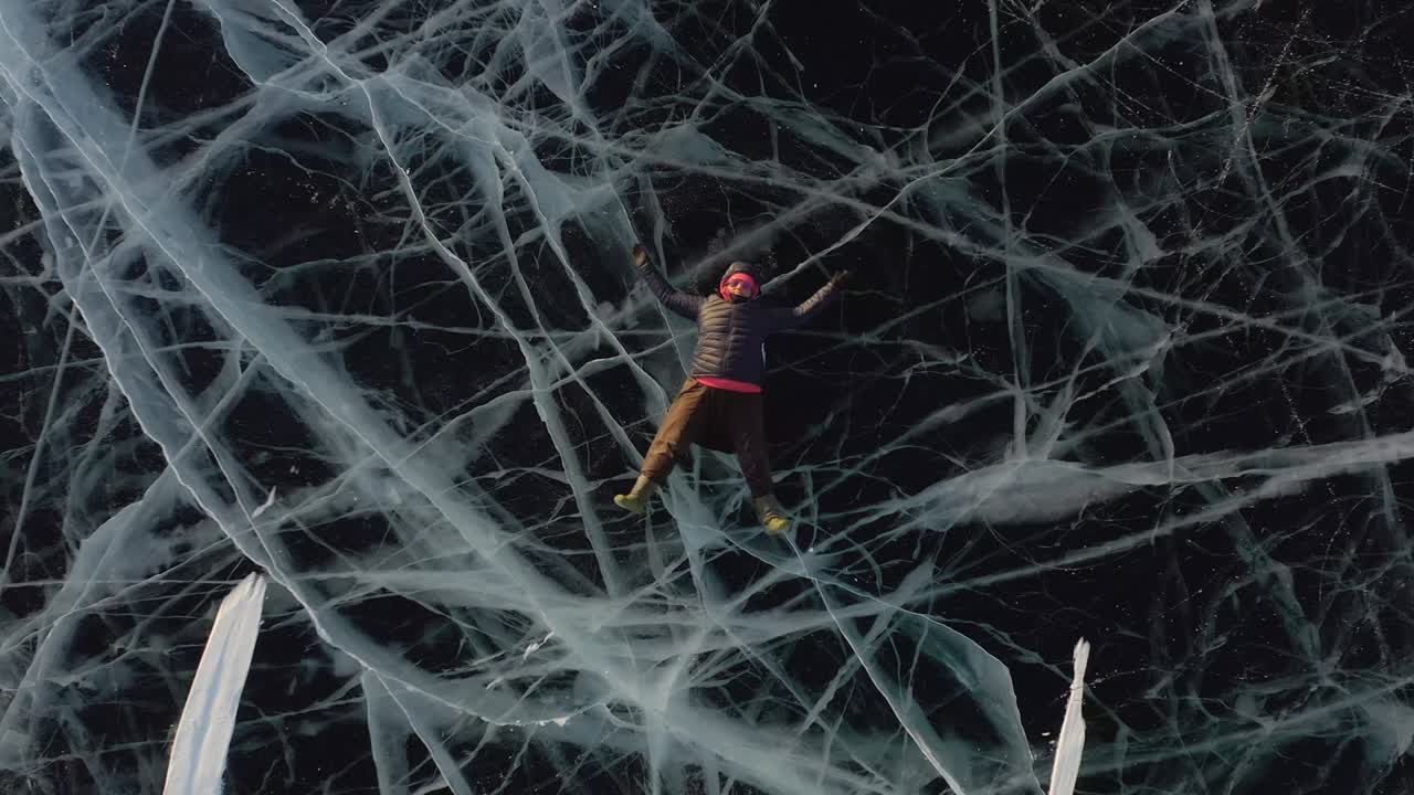 한 소녀가 따뜻한 옷을 입고 으로 팔과 다리를 흔들며 겨울에 얼음 위에 누워 있습니다.