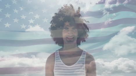 animation of flag of usa over smiling african american man on beach