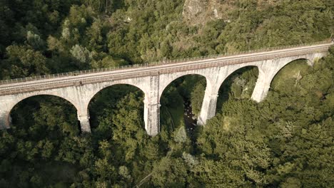 drone 4k view zooming in on the ponte ferroviario sul fiume serchio, a train bridge near garfagna, a historical region in central italy