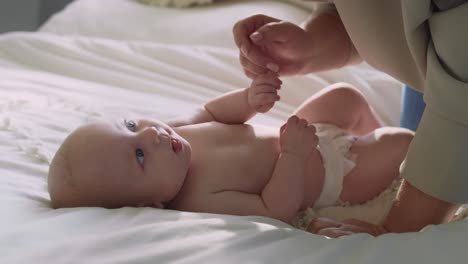 unrecognizable woman playing with her newborn baby lying on the bed