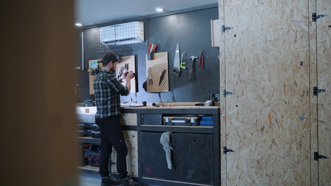 View of man tinkering in a workshop through a partially open door