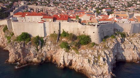 Aerial-Reveal-Of-The-Dubrovnik-City-Walls,-With-Small-Boats-In-The-Beautiful-Mediterranean-Sea-In-The-Stunning-Country-Of-Croatia