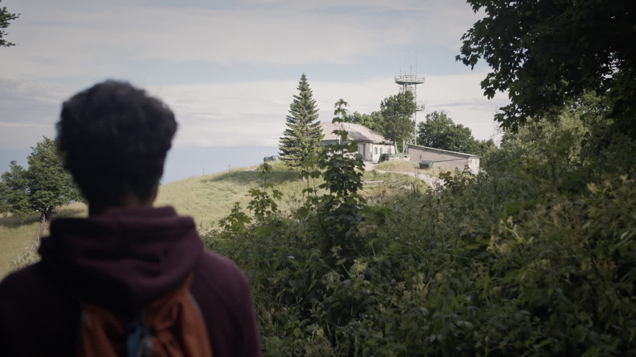 trdinov vrh 산 정상에 있는 산장을 향해 걸어가는 등산객을 짐벌로 뒤에서 추적하면 근처에 라디오 타워가 있습니다.