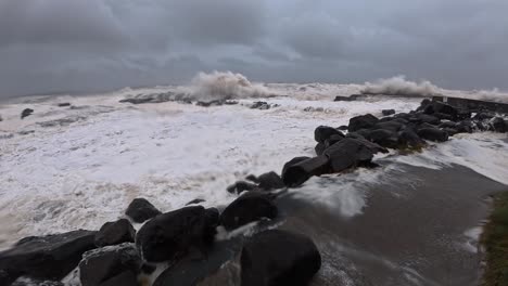 swell hitting the seawall rocks on froggies beach during cyclone alfred in australia. - handheld shot