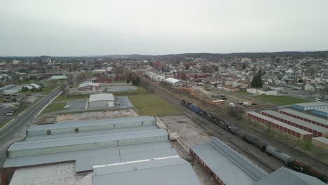 Aerial-drone-view-of-a-train-traveling-through-a-massive-industrial-facility