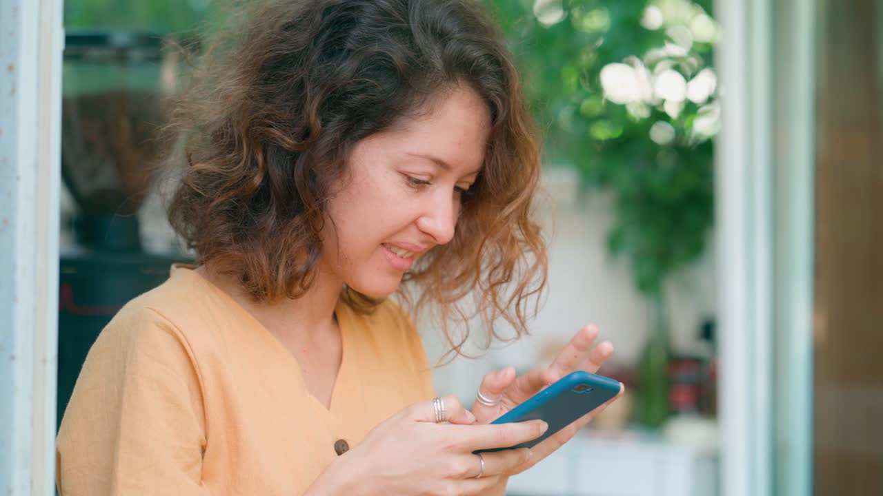 Giovane donna che sorride mentre digita sullo smartphone