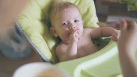 mother waits for son to open mouth feeding baby with soup