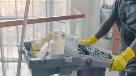 close up view of cleaning man hands carrying cleaning cart inside an office building