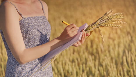 woman agronomist writing data in wheat field. agriculture research concept