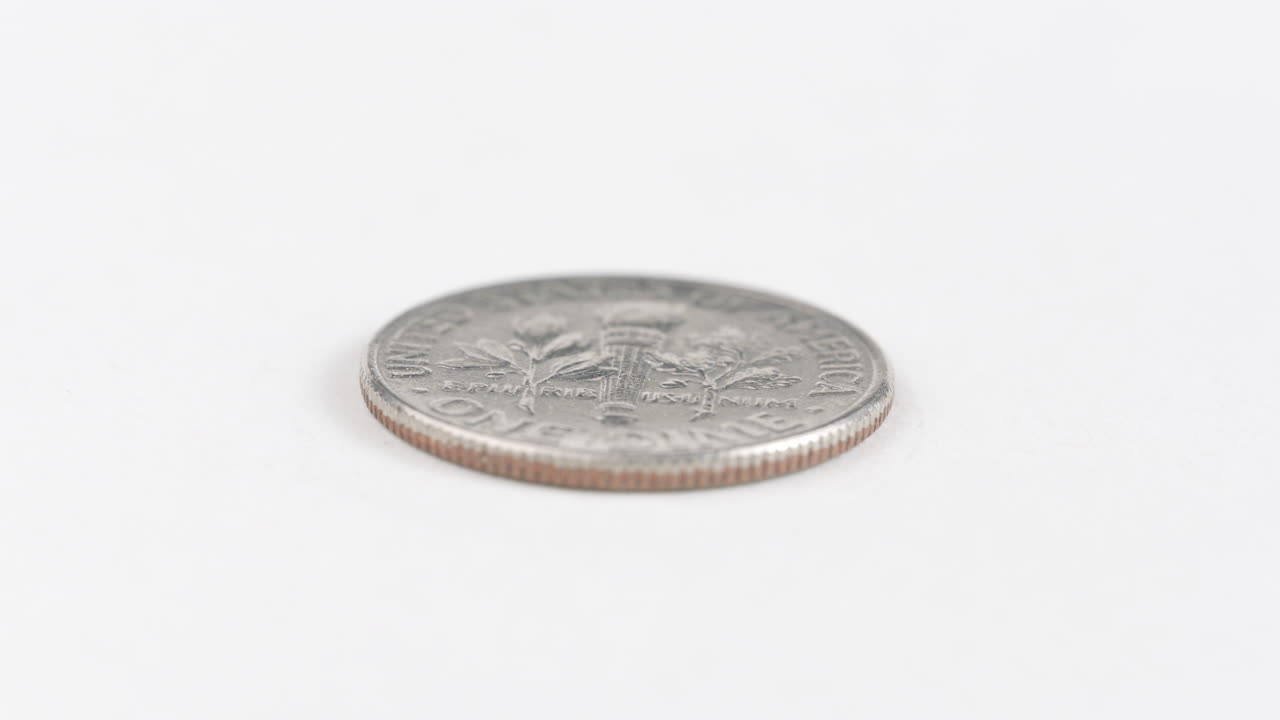 una moneda de diez centavos colocada plana sobre una mesa blanca