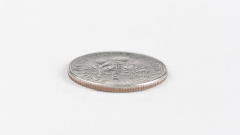 una moneda de diez centavos colocada plana sobre una mesa blanca