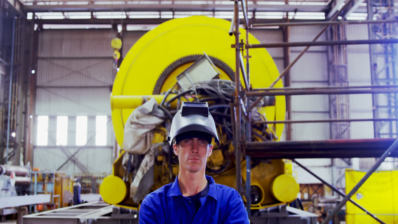 ingegnere maschio in piedi con le braccia incrociate in officina 4k