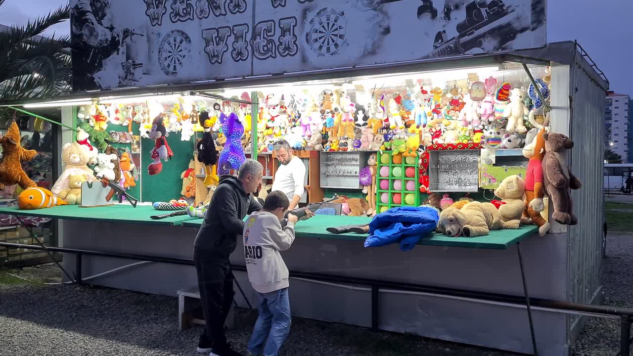 Family playing a skill game at a fairground at night
