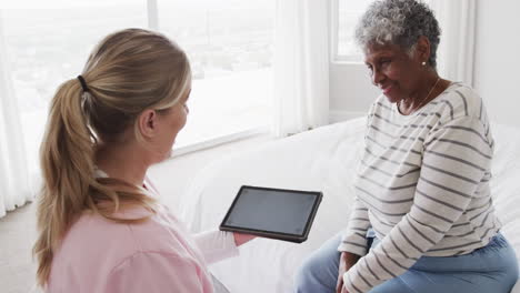 enfermeira caucasiana e mulher afro-americana sênior usando tablet, espaço de cópia, câmera lenta