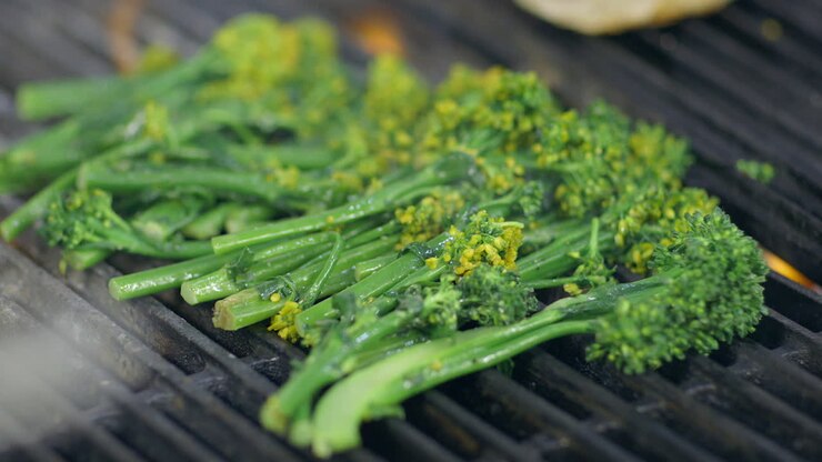 Fresh broccolini on a hot grill in a restaurant kitchen, close up