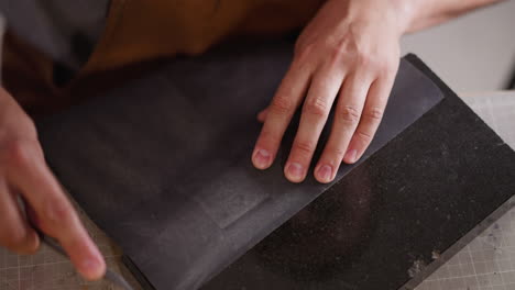 worker sharpens cutter with sandpaper at table in workshop