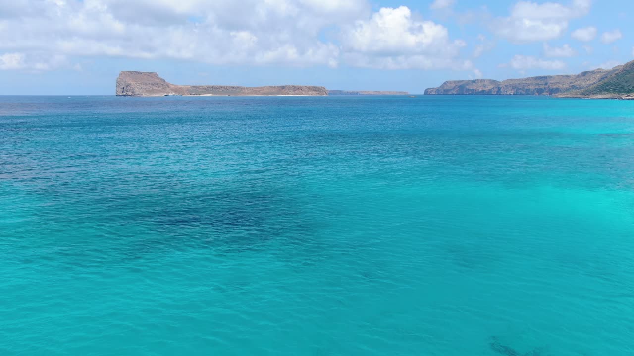 Approaching Gramvousa beach rocky island near Balos Beach in Crete Greece with blue turquoise-colored water, Aerial flyover shot