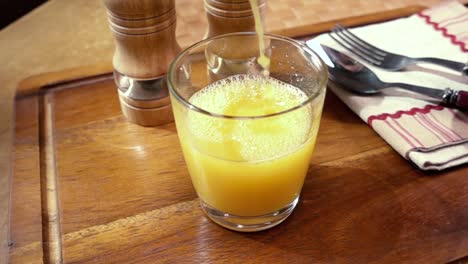 Jugo-De-Naranja-Vertido-En-Un-Vaso,-El-Desayuno-De-La-Mañana.-Cámara-Lenta-Con-Seguimiento-De-Rotación.