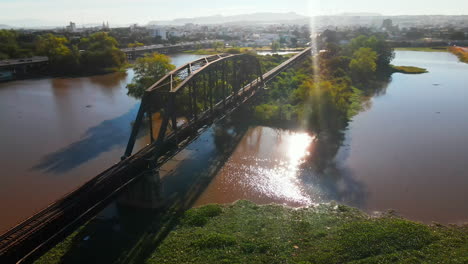 drone view of a rusty railway steel bridge over a river