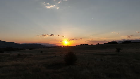 Sunset-behind-a-lone-tree-on-a-mountain-horizon