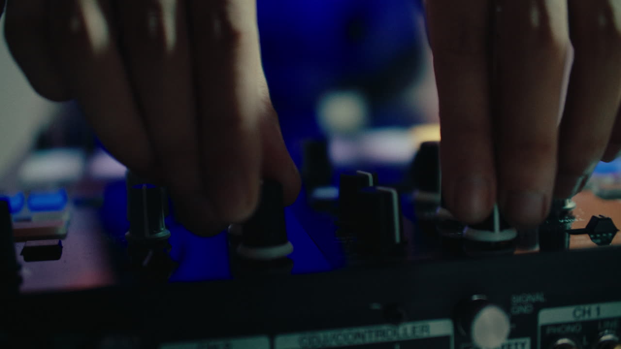 close up of young male dj controlling the mixer volume during a set in a party concert music festival