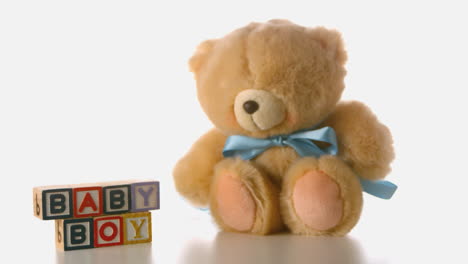 fluffy teddy bear falling besides baby blocks