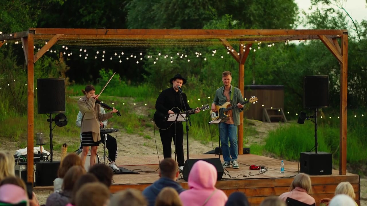 Musical Trio Performing Live on Outdoor Stage at Sunset