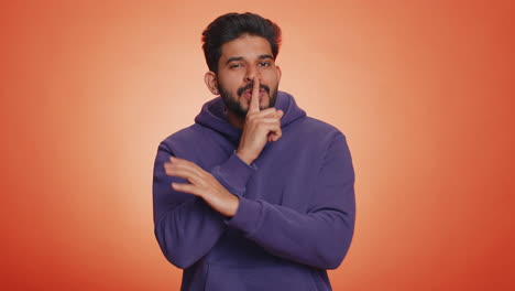 Young-indian-man-presses-finger-to-lips-makes-silence-gesture-sign-do-not-tells-secret,-stop-gossip