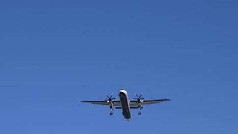 turboprop passenger airplane flying overhead for landing, low angle