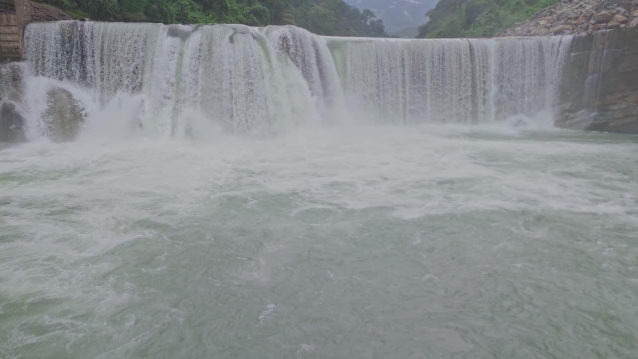 A breathtaking aerial view of a beautiful waterfall cascading through lush green mountains, showcasing the untouched beauty of nature, flowing water, and serene landscape scenery