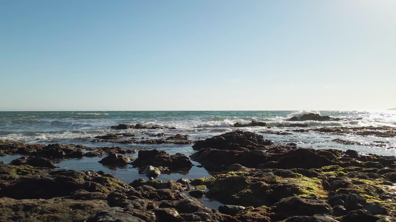 caminando por una playa rocosa, de derecha a izquierda