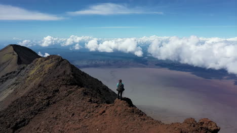 adventurous hiker on a volcanic mountain peak with cloudscape