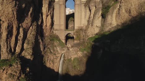 waterfall under the puente nuevo bridge in ronda, spain