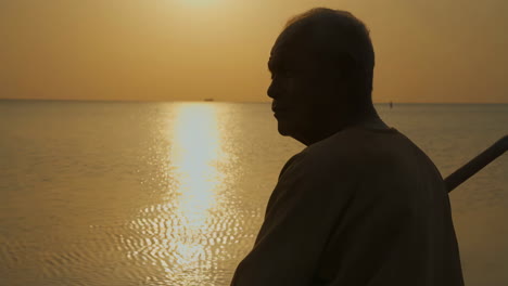 man's silhouette at sunset over water