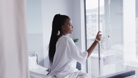 African-american-female-patient-sitting-on-bed-in-hospital-room,-slow-motion