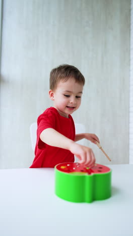 focused caucasian baby plays with a toy at home. smiling toddler is busy with his educational toy. vertical video.