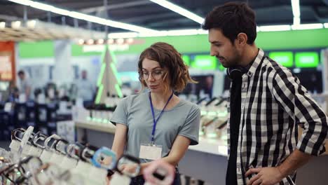 en la tienda de electrónica, una consultora da consejos profesionales a un joven que considera comprar un nuevo teléfono inteligente y